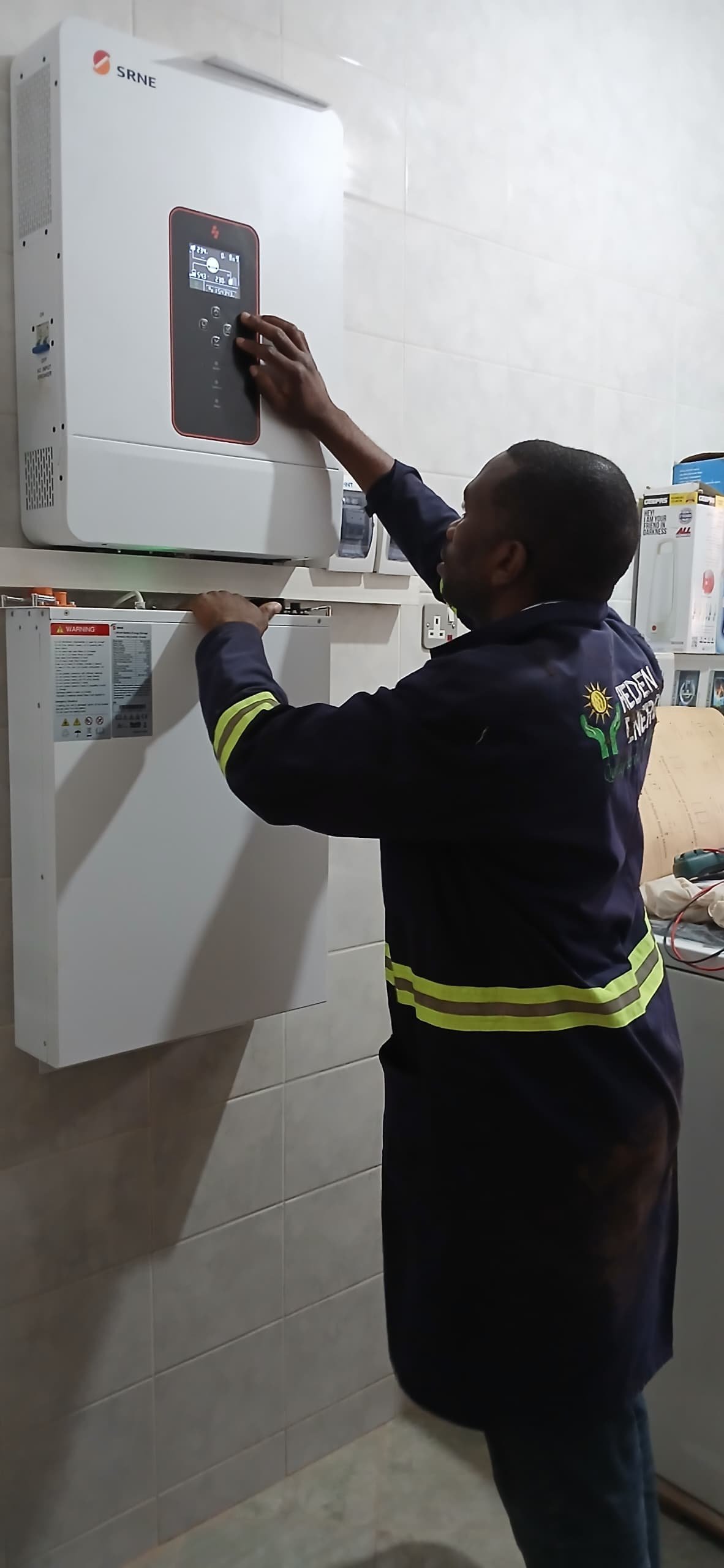 Technician in safety gear operating a SRNE white water heating system mounted on a white tiled wall